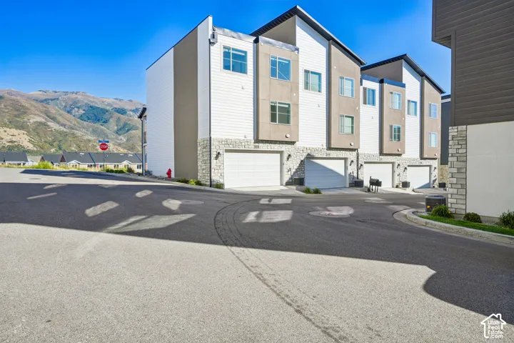 Multi-story townhomes featuring modern architectural design, white siding, and stone accents