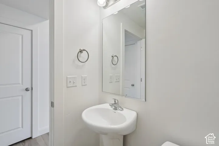 Pedestal sink with chrome faucet, large rectangular mirror, and light fixture