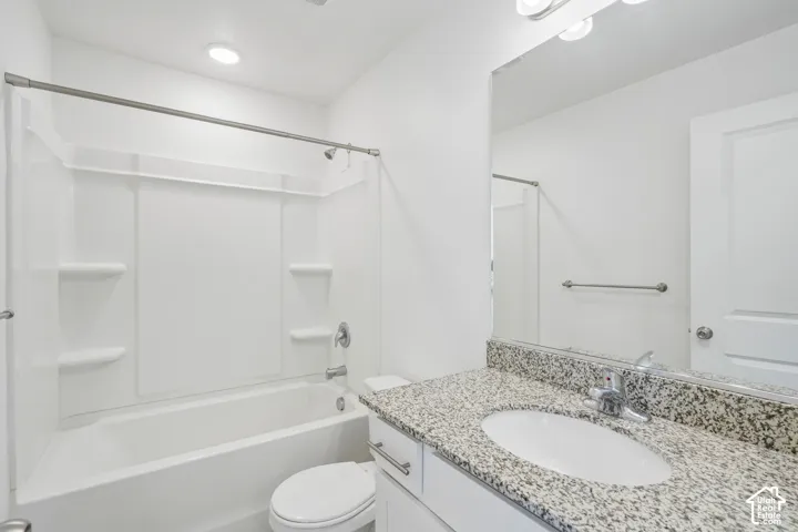 White vanity with a speckled countertop, a built-in sink, and a large mirror