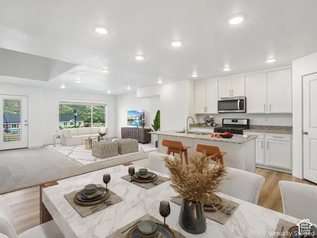 Open-concept living area with recessed lighting, light wood-finish flooring, and a kitchen island with seating