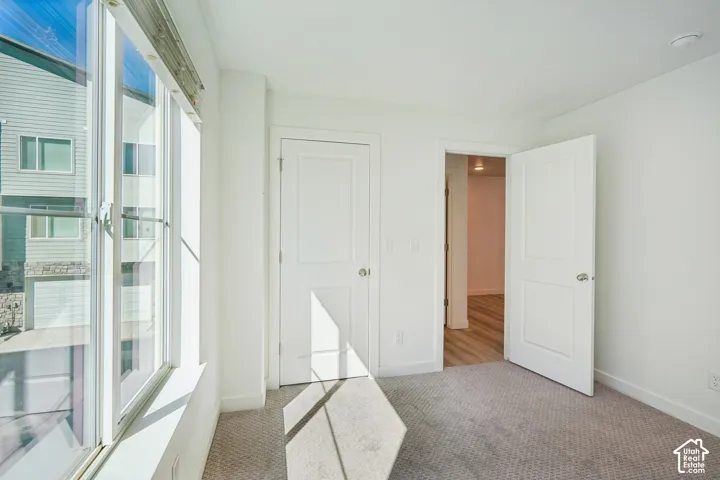 Bright interior featuring a large window, white trim, recessed lighting, and carpeted flooring