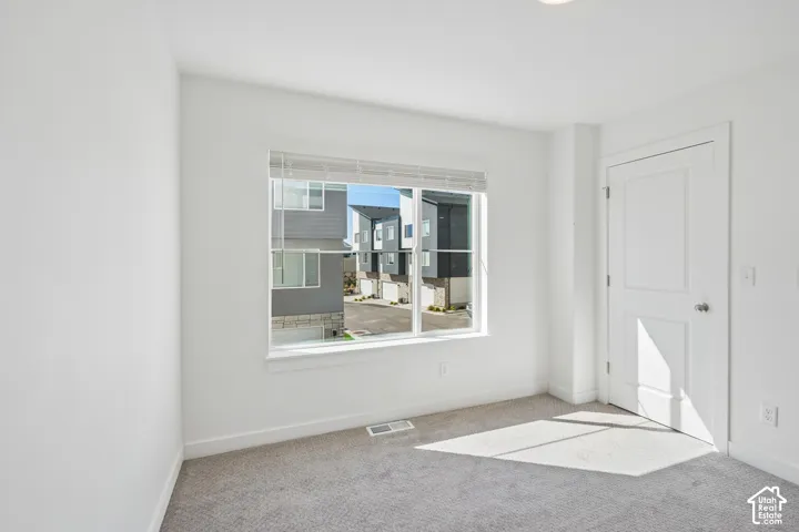 Recessed ceiling lighting, white interior walls, window with blinds, gray carpet, and a white paneled door