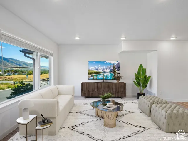 Expansive windows showcasing mountain scenery, recessed lighting, and light wood-finish flooring