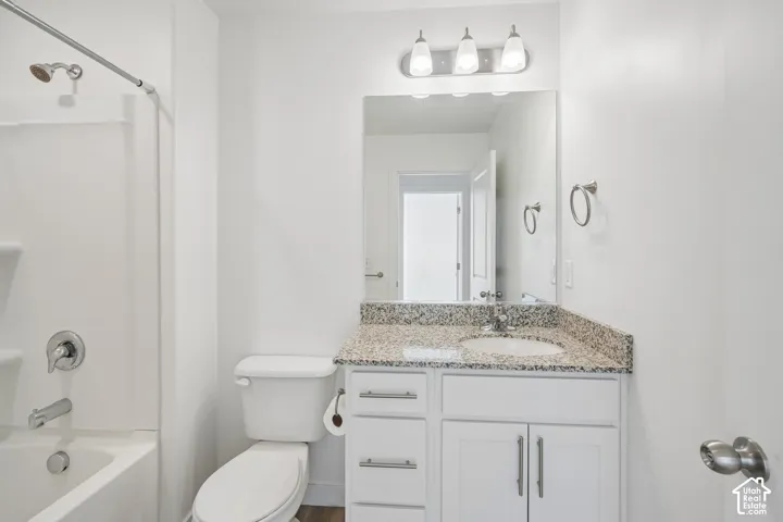 White vanity with a speckled countertop, a single basin sink, and chrome fixtures