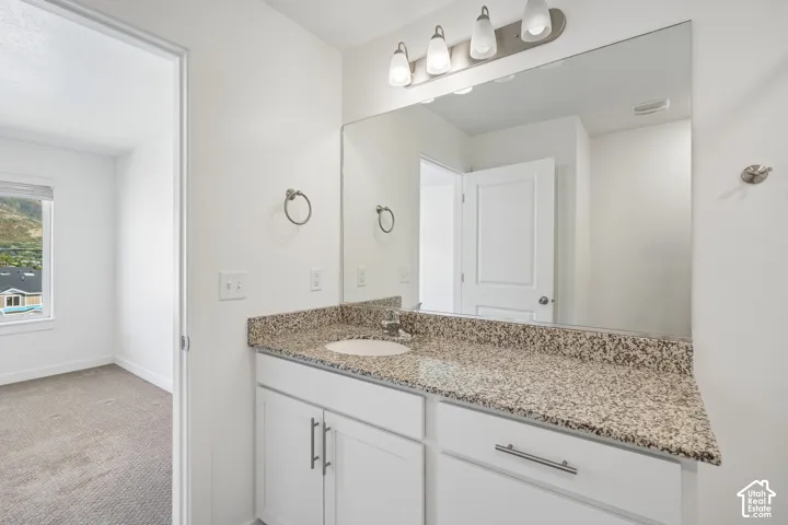 White vanity with granite-style countertop, integrated sink, and brushed nickel hardware