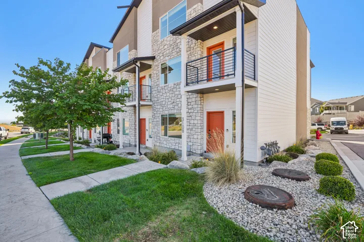 Modern exterior featuring stone veneer, horizontal siding, and balconies with black metal railings