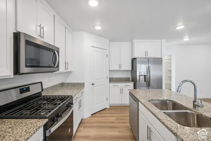 Kitchen featuring white shaker cabinetry, stainless steel appliances, granite countertops, and wood-finish flooring