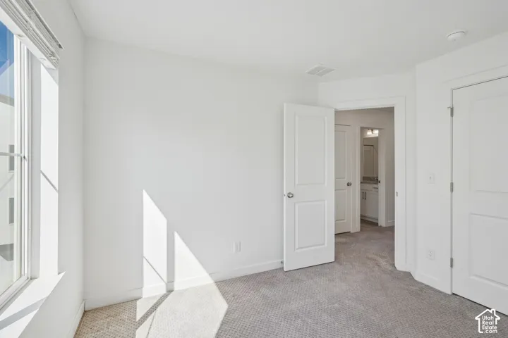 Plush carpet flooring, white interior doors, and a window with blinds