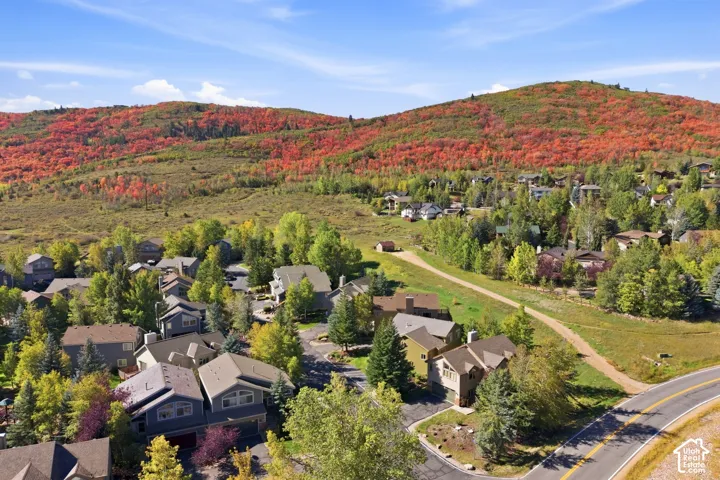 Residential properties with pitched roofs, surrounding hills with dense foliage, and paved roads