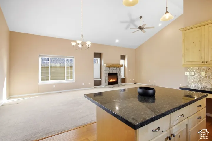 Kitchen island with dark countertop, light wood cabinetry, and a mosaic tile backsplash
