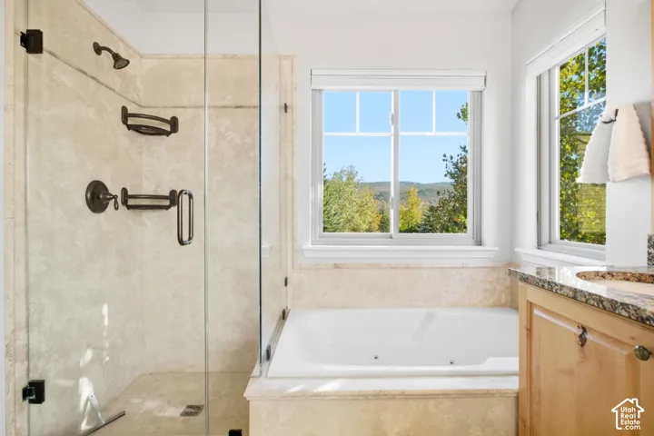 Glass-enclosed shower with bronze fixtures and stone-finish tiling