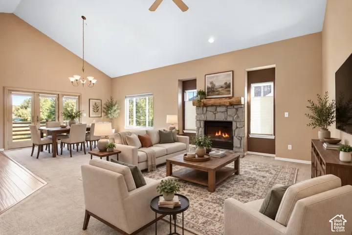 Vaulted ceilings, a stone fireplace with a wood-beam mantel, glass-panel French doors, and a chandelier-lit dining area