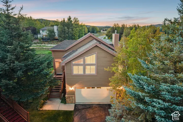 Multi-level exterior with horizontal siding, a prominent chimney, and an attached garage