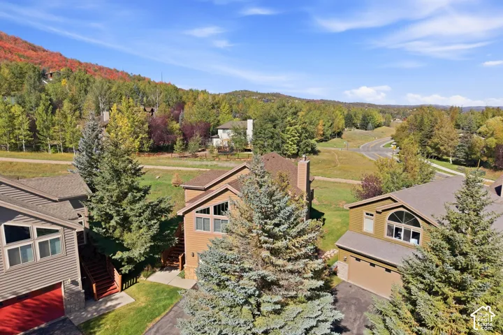 Property featuring a sloped roof, an attached garage, a multi-pane window, and surrounding mature trees