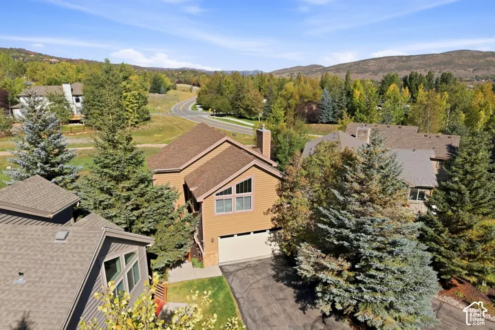 Wood-sided exterior with a multi-level roofline, attached garage, and prominent chimney