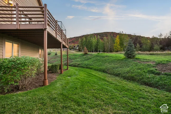Expansive backyard featuring a manicured lawn, established shrubs, and a multi-level deck structure with support columns