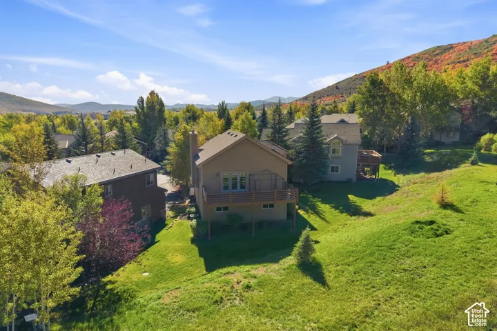 Terraced lot featuring a wood deck, mature trees, and a mountain backdrop