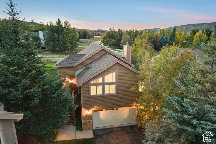 Multi-level residence featuring horizontal siding, a stone facade, and multi-pane windows