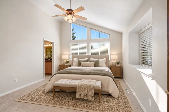 Vaulted ceiling with a ceiling fan, multiple windows with blinds, recessed window nook, and wall-to-wall carpeting