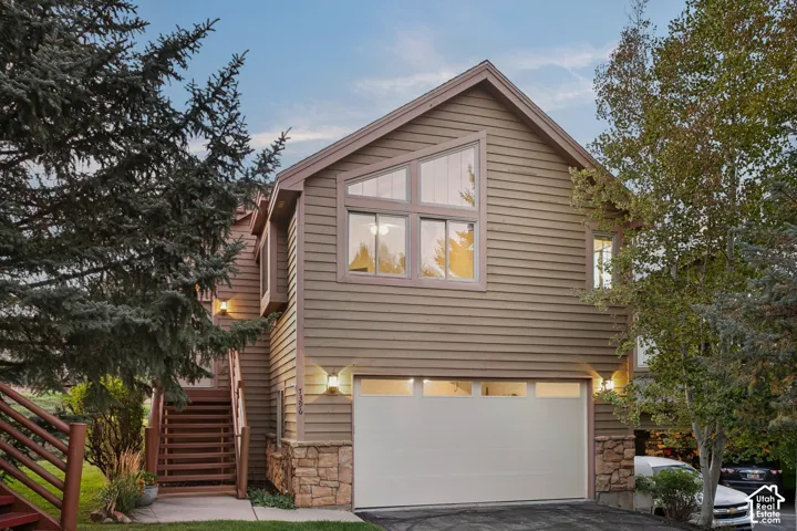 Property exterior featuring horizontal siding, a two-car garage, stone accents, and an exterior staircase
