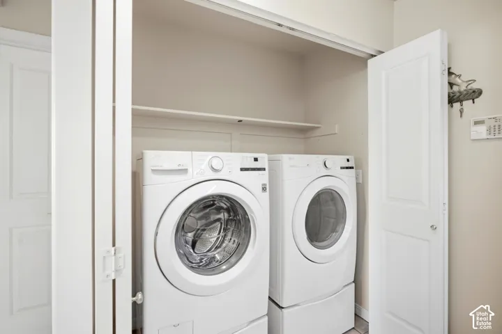 Dedicated laundry closet with white bifold doors and an integrated storage shelf