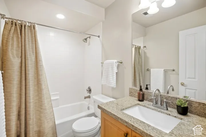 White subway tile shower surround with a built-in tub, a vanity with a light-colored stone countertop, a rectangular undermount sink, and a large wall-mounted mirror