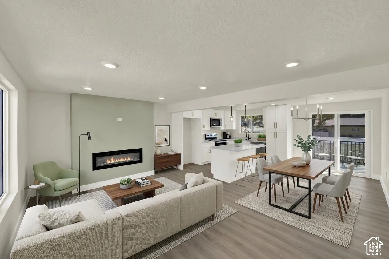 Open-concept living space featuring wood-finish flooring, a linear fireplace, recessed lighting, and a sliding glass door