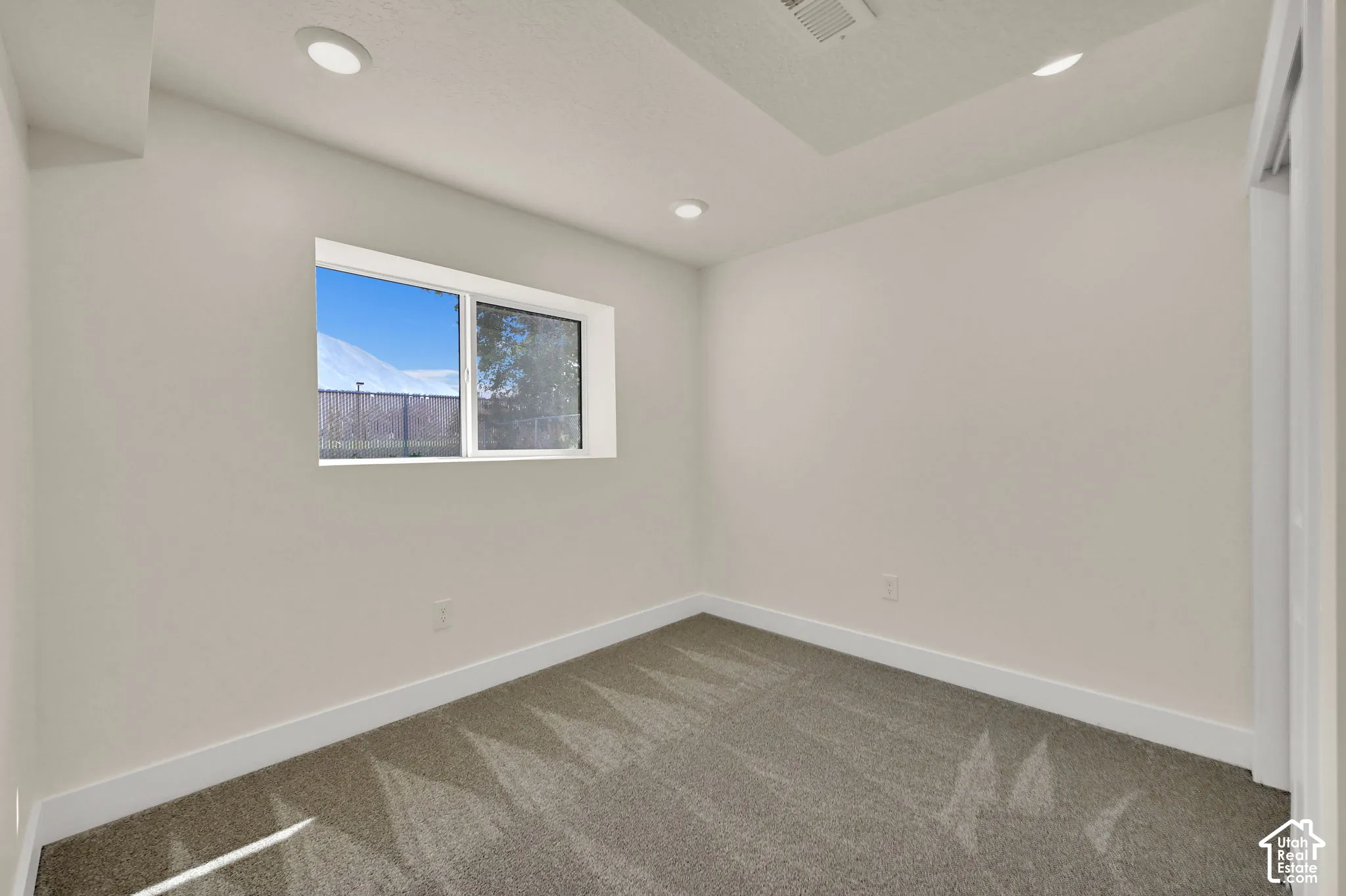 Recessed lighting, light gray carpeting, neutral wall paint, and a double-pane window