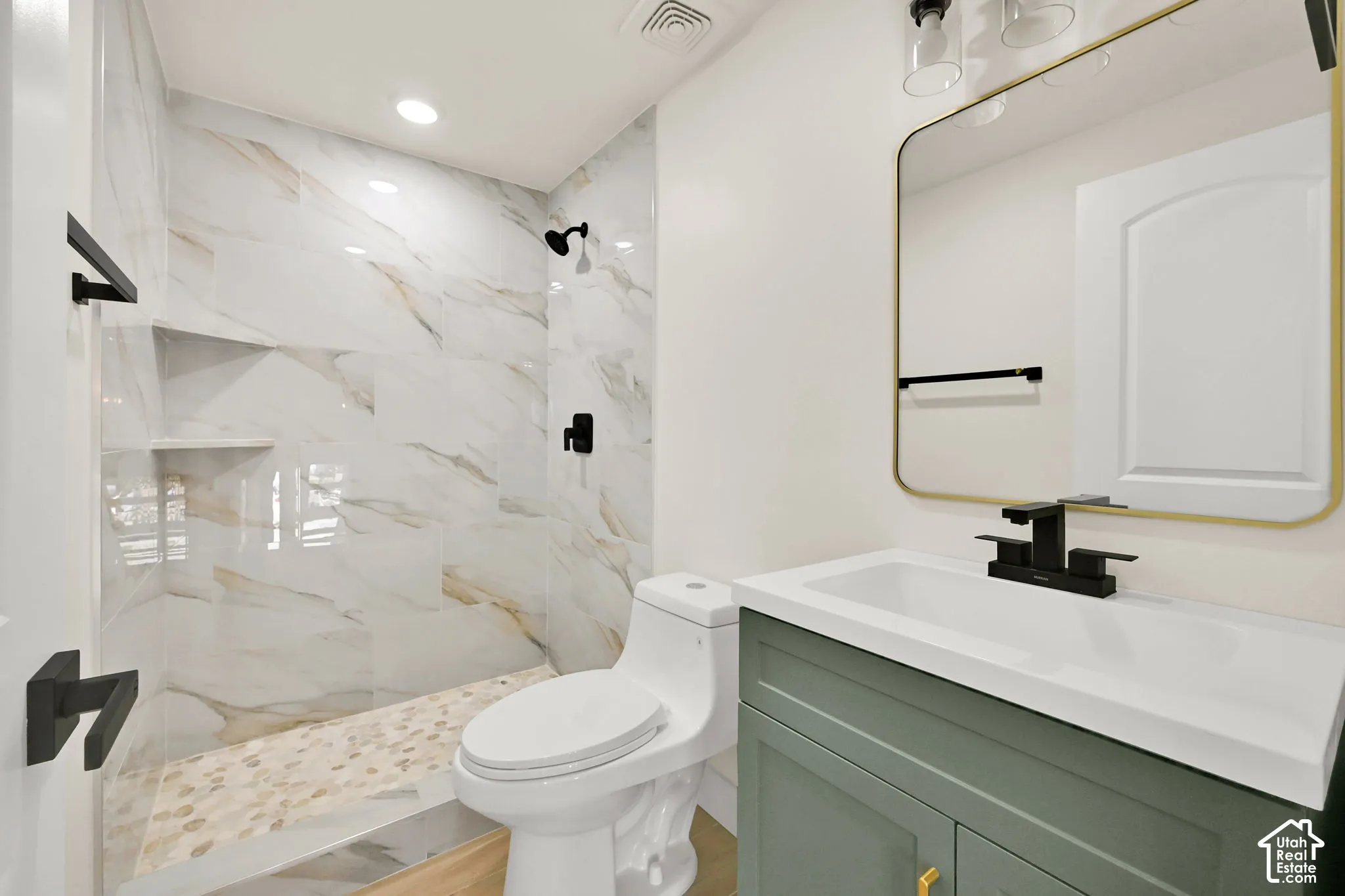 Walk-in shower with large format tile surround, built-in shelving, and river rock flooring