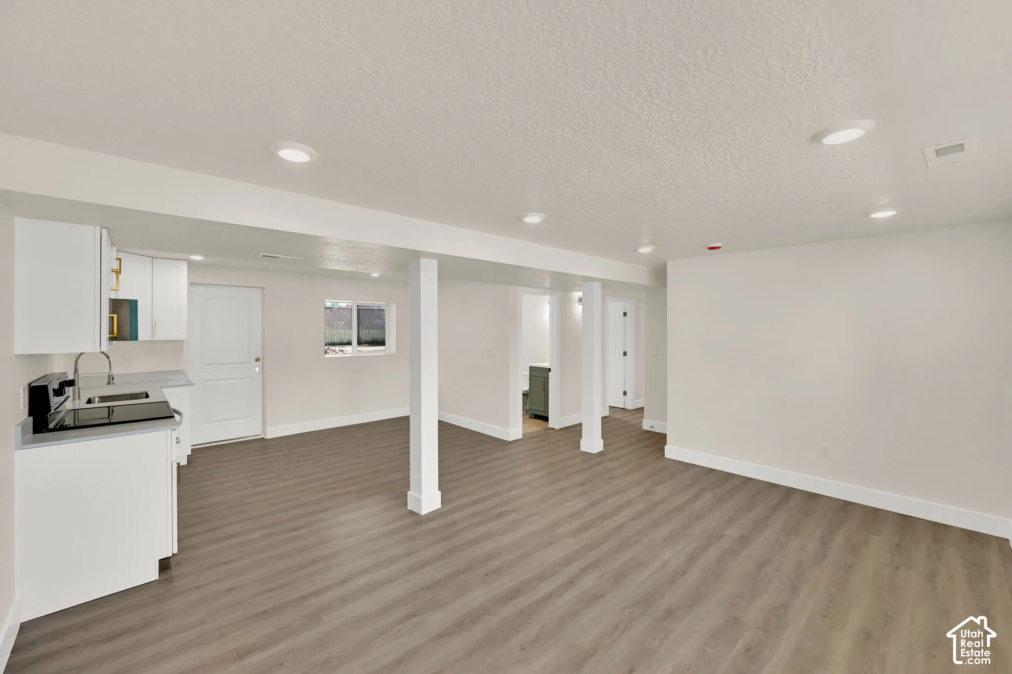 Spacious open-concept room with wood-finish flooring, recessed lighting, and white walls