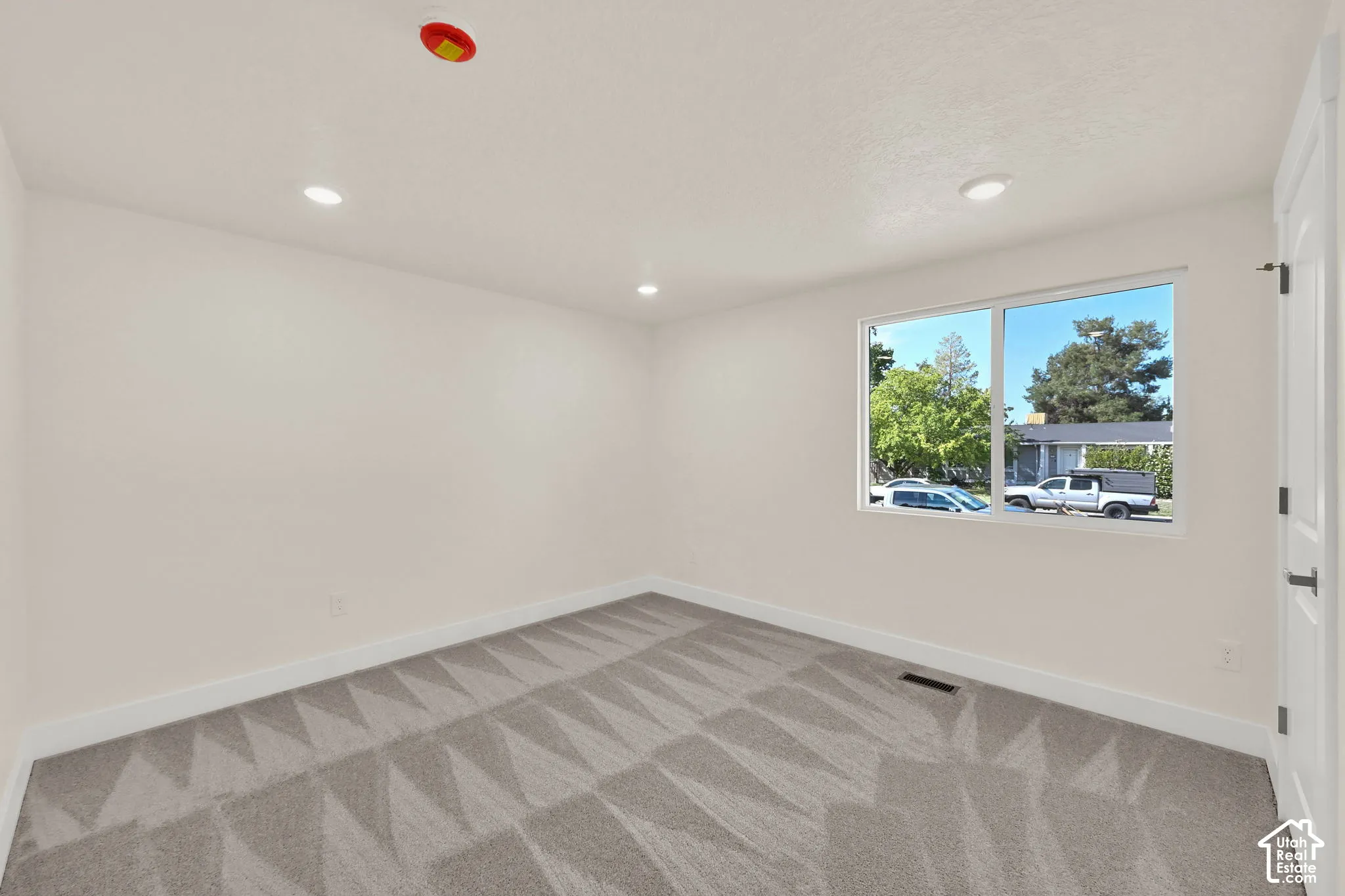 Recessed lighting illuminates neutral walls and patterned carpeting