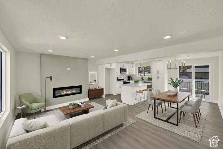Open-concept living space featuring wood-finish flooring, a linear fireplace, recessed lighting, and a sliding glass door