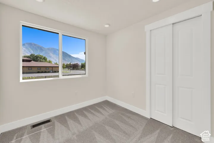 Recessed ceiling lighting, mountain scenery, white trim, sliding closet doors, and patterned carpet