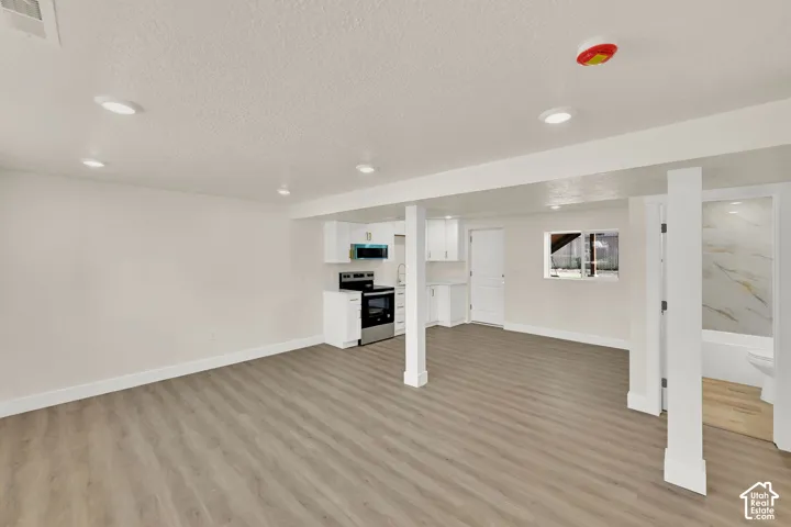Open-concept living area with wood-finish flooring, recessed lighting, and a compact kitchen