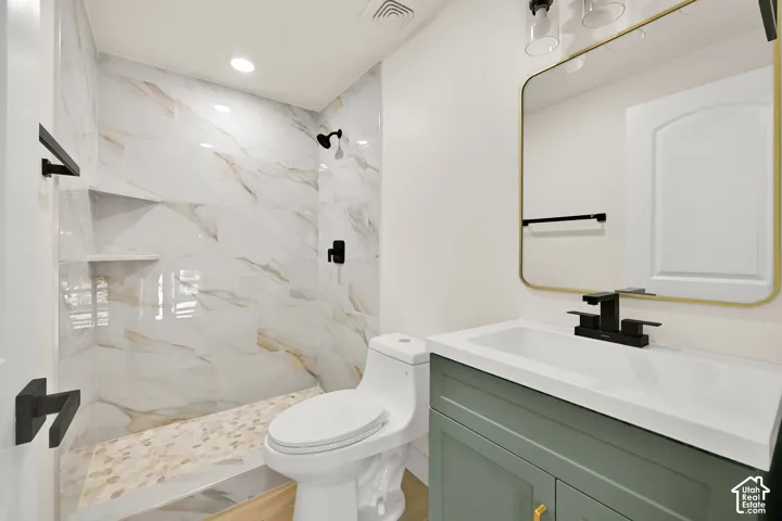 Walk-in shower with large format tile surround, built-in shelving, and river rock flooring