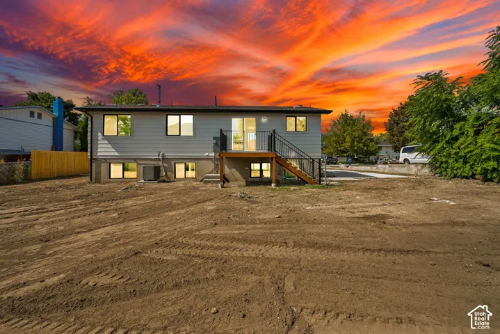 Lower-level windows, full-height windows, a ground-level patio door, and a raised wood deck with dark metal railings