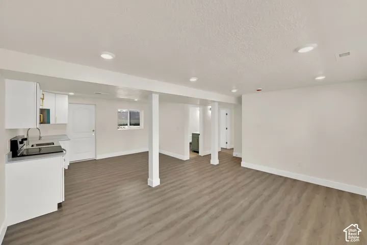 Spacious open-concept room with wood-finish flooring, recessed lighting, and white walls