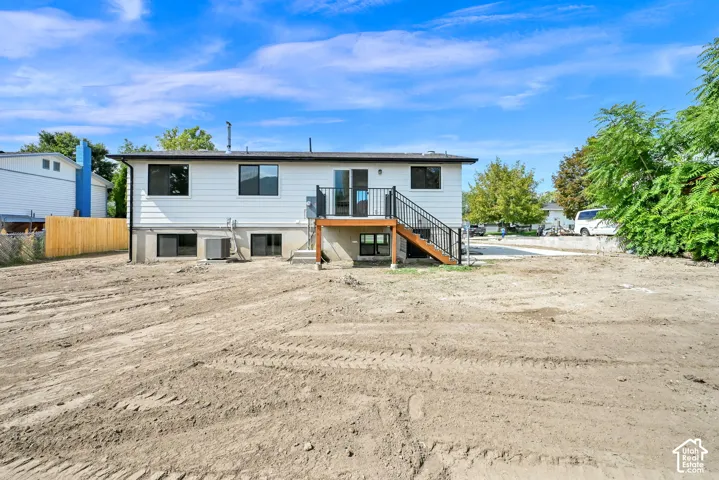 White exterior with a dark-frame sliding door, dark-frame windows, and a wood-finish deck with black railings