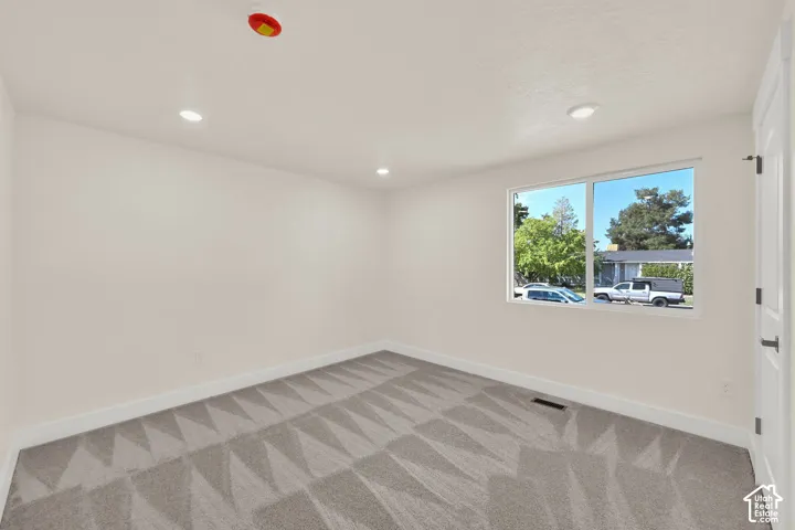 Recessed lighting illuminates neutral walls and patterned carpeting