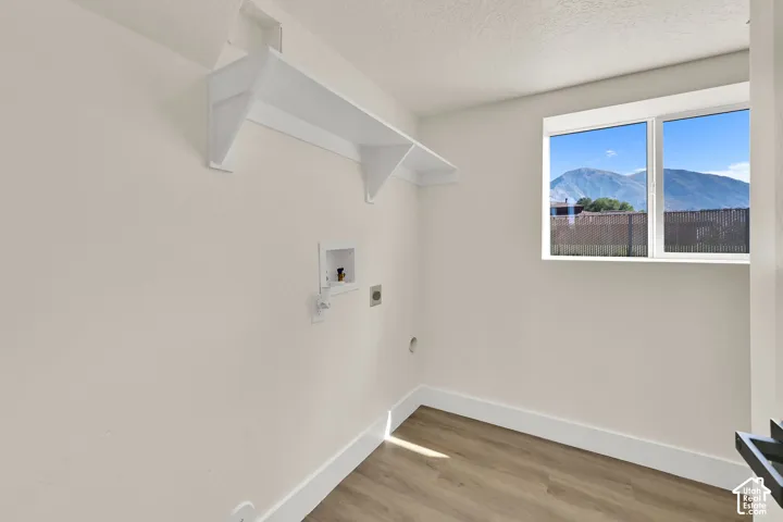 Laundry area featuring wood-finish flooring, a double-paned window, and a built-in wall shelf