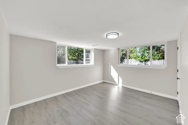 Neutral wall tones, wood-finish flooring, multiple windows, and a flush-mount ceiling light