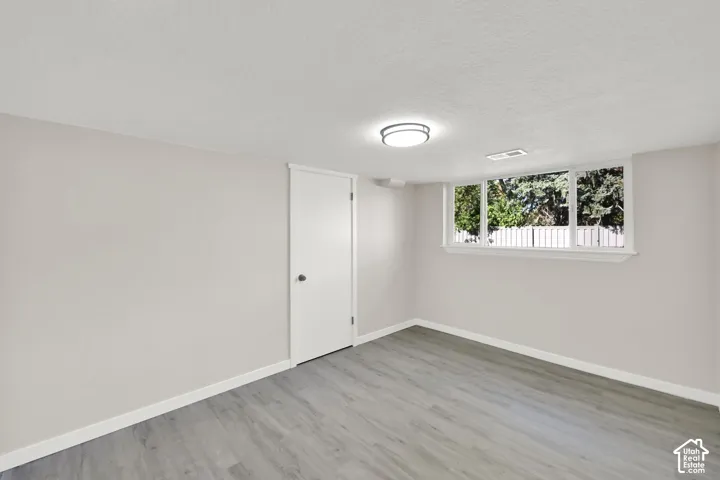 Neutral wall color, wood-finish flooring, white trim, flush-mount ceiling light, and a window with a white frame