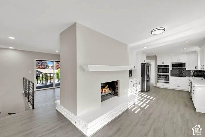 Modern open-concept living space anchored by a two-sided gas fireplace with white surround and linear mantel