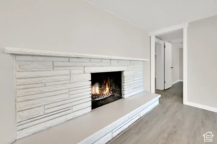 Stone-clad fireplace with mantel and hearth, light neutral wall paint, and wood-finish flooring