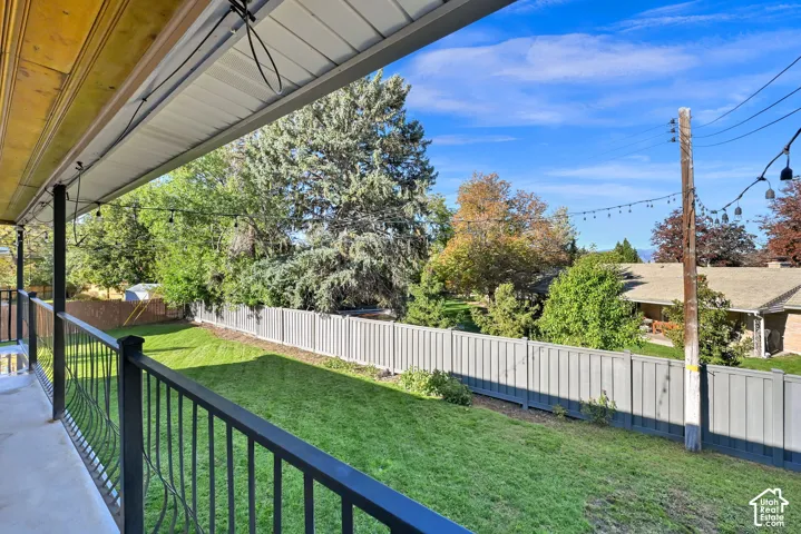 Expansive backyard with a manicured lawn, framed by a privacy fence, and mature trees