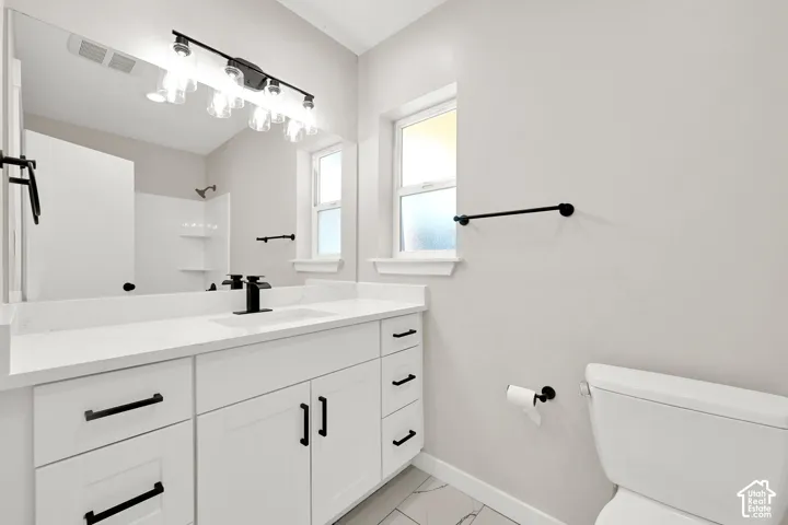 White vanity with black hardware, integrated sink, and white countertop