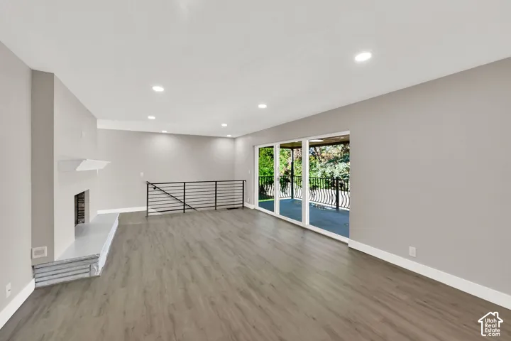 Spacious room featuring wood-finish flooring, a fireplace with a mantel, and recessed lighting
