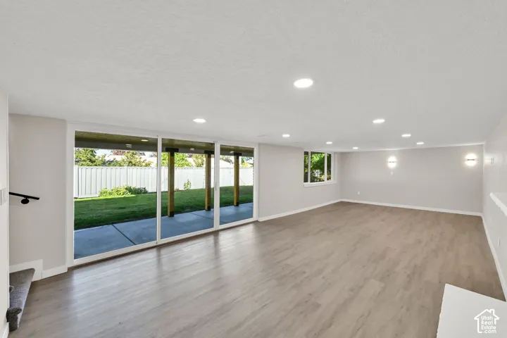 Spacious open-concept room with wood-finish flooring, recessed lighting, and wall sconces