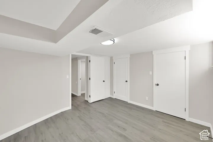 Recessed ceiling details, wood-finish flooring, white trim, white paneled doors, and an overhead flush-mount light fixture