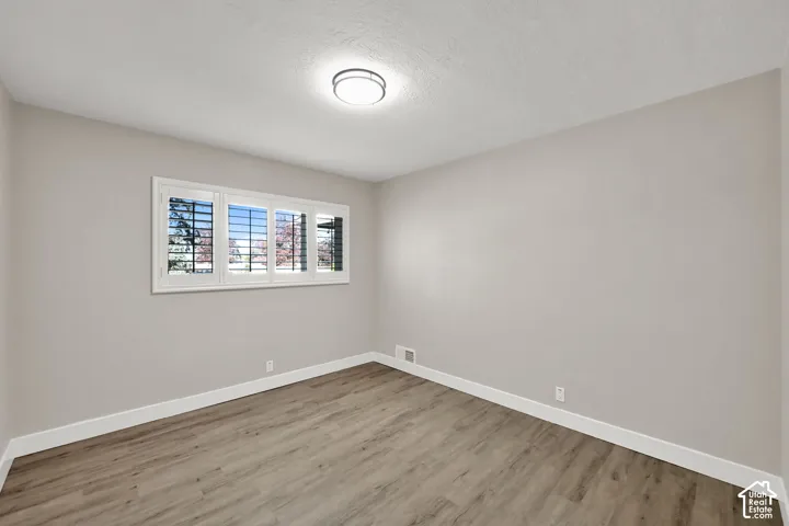 Wood-finish flooring, white baseboards, and neutral wall paint